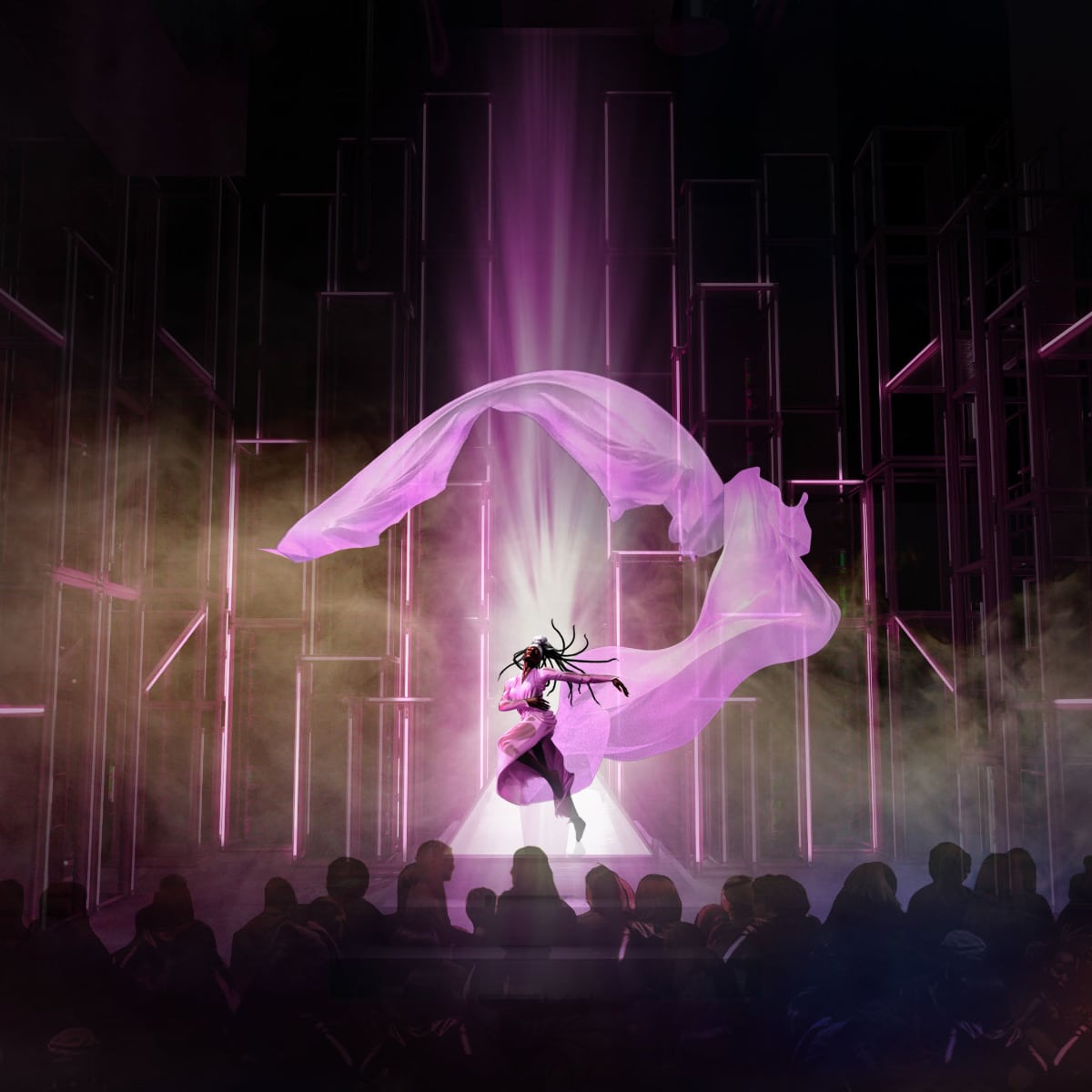 Performer on stage with flowing pink fabric, surrounded by purple lighting, in front of an audience.