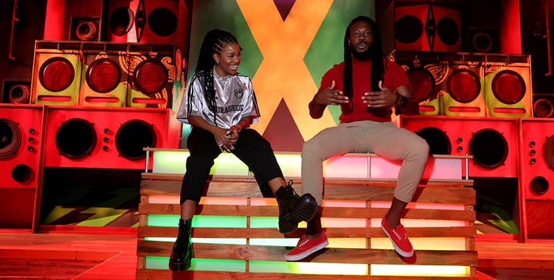 Two performers sit on the stage at Hope Road